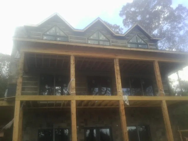 Dormers and porch framing on a large log home under construction — Roof Coating work by our crew in Adrian